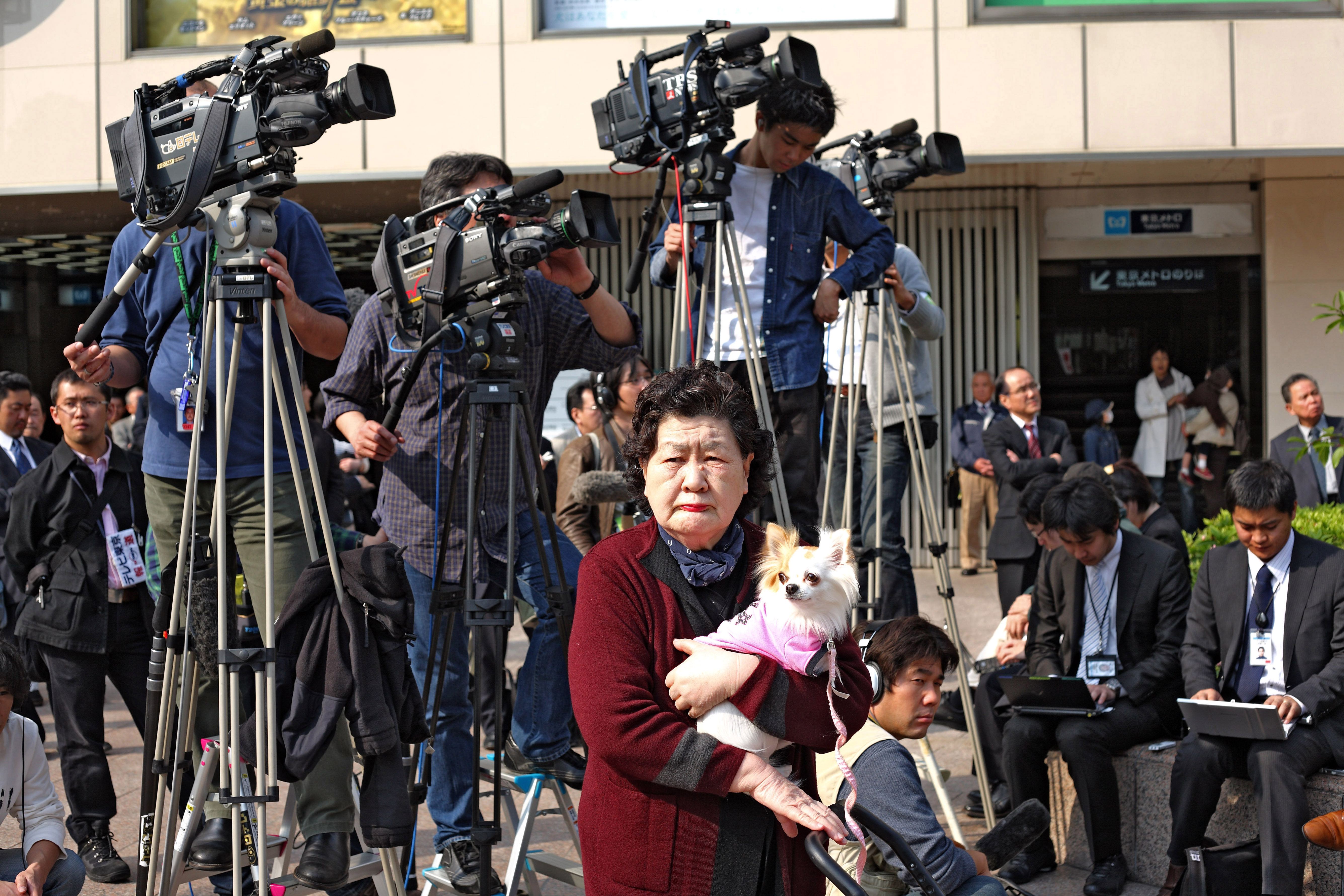 Au carrefour de Ginza, le politicien Naoto Kan s'adresse à la foule des journalistes et à l'unique spectatrice qui l'écoute.