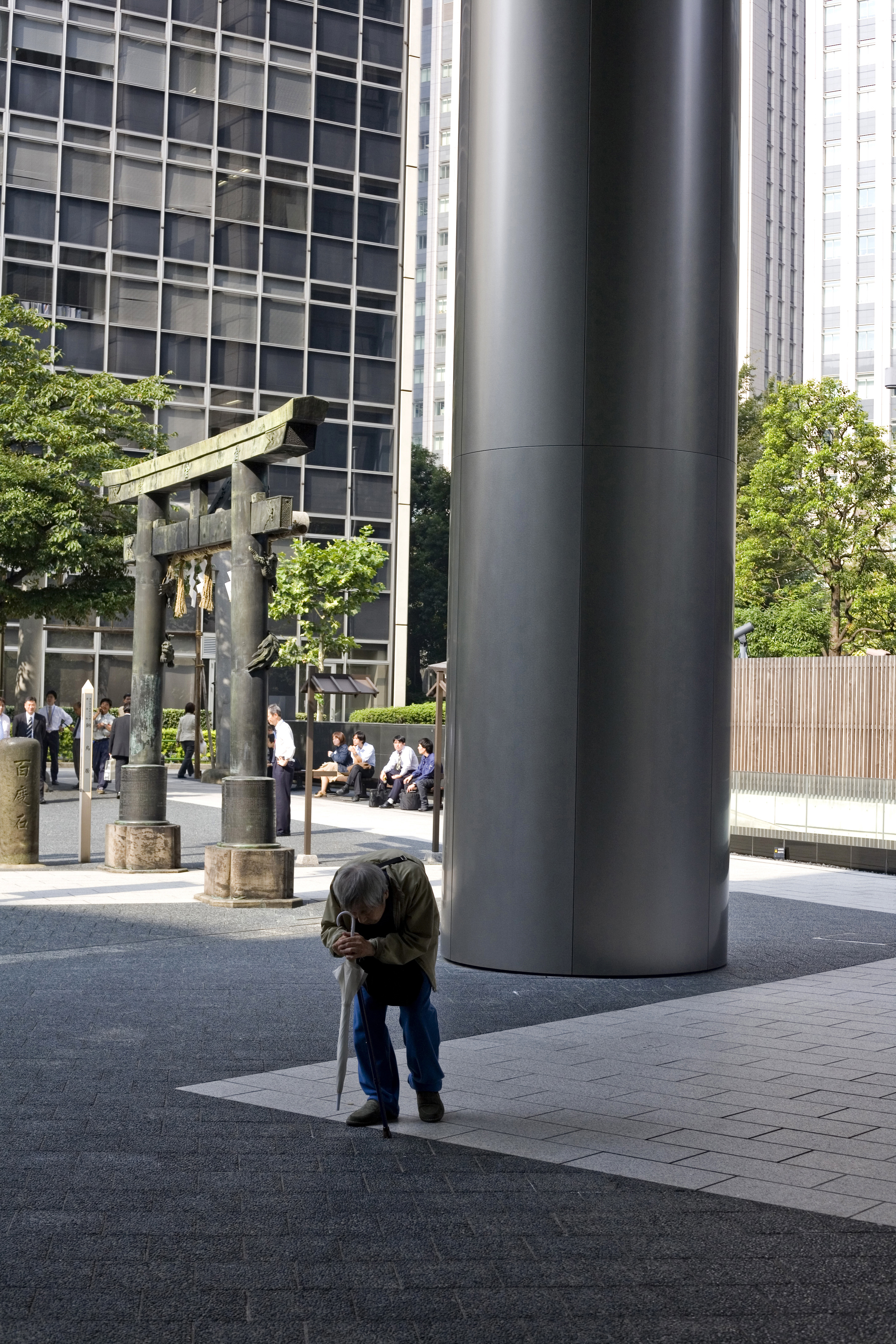 Un immeuble ultra moderne jouxte un temple à Toranomon Tokyo.

Un viel homme rentre du temple et passe sous l'immeuble moderne